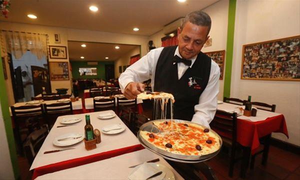Garçom Roberto Silva serve pizza de muçarela, um dos sabores preferidos do consumidor brasileiro (FOTO: Celso Luiz/DGABC)